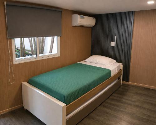 a small bed in a small room with a window at CulturaHumana Guesthouse in Panama City