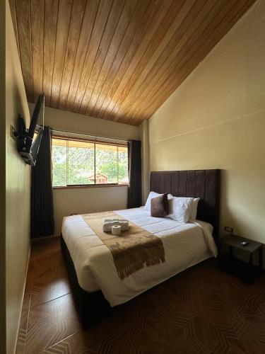 a bedroom with a large bed with a wooden ceiling at Andher Palaces Hotel in Ollantaytambo