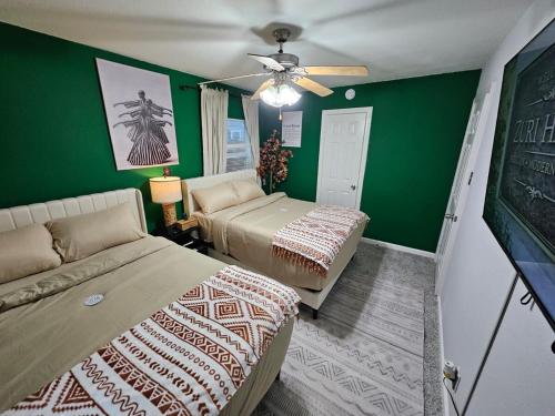 a green room with two beds and a couch at 3BR Houston with Grill, Hot Tub and Game Room near NRG, Downtown and Hobby Airport in Houston