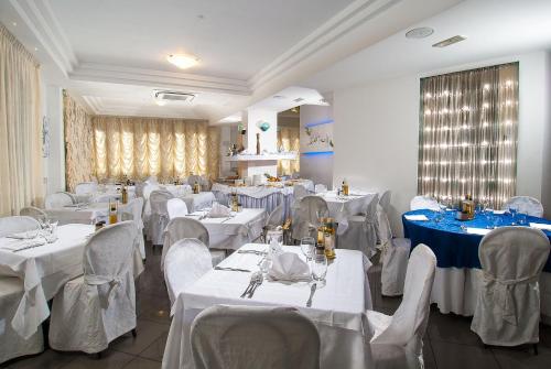 a dining room with white tables and chairs and white tablesearcher at Hotel Mediterraneo in Pesaro