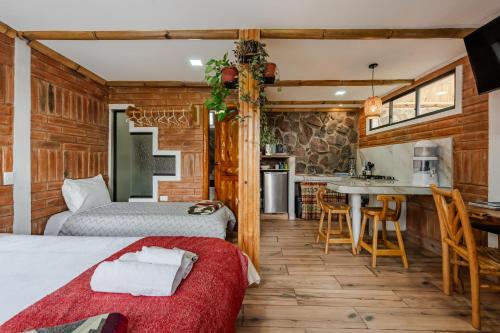 a bedroom with two beds and a kitchen with a table at Watzara Wasi Studios en Cotacachi in Cotacachi