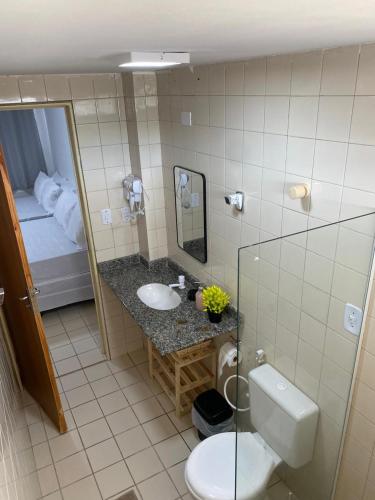 a bathroom with a toilet and a sink and a bed at Family Beach flat - frente ao mar in Barra de São Miguel
