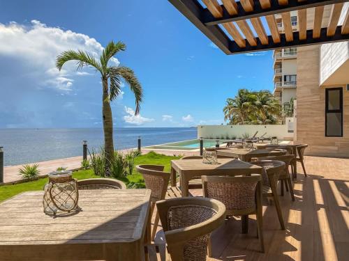 a patio with tables and chairs and a view of the ocean at Distrito Puerto by Andiani Travel in Puerto Morelos