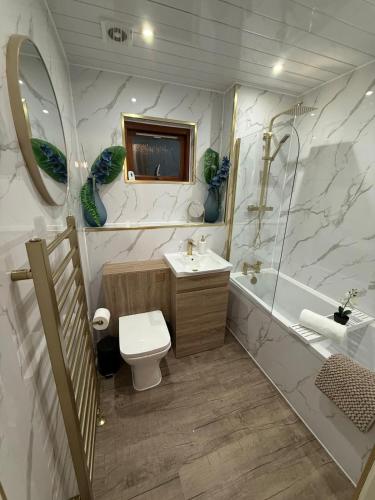 a bathroom with a toilet and a sink and a tub at 2 Bed Entire Upper Cottage Flat in Central Glasgow in Glasgow