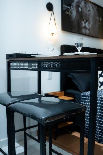 a black desk with a stool and a table with wine glasses at Studio confort com ar Centro de Niteroi in Niterói