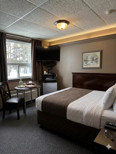 a hotel room with a bed and a table at Beaver Motel in Wawa