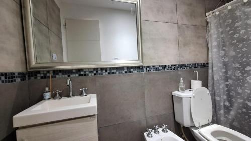 a bathroom with a sink and a toilet and a mirror at Apart Z Alberdi in Belén de Escobar