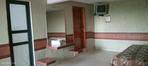 a room with a bed and a mirror and a television at Campo Real Actopan in Cedro