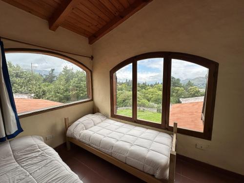 a room with two beds and two large windows at Casa Tafi del Valle in Tafí del Valle
