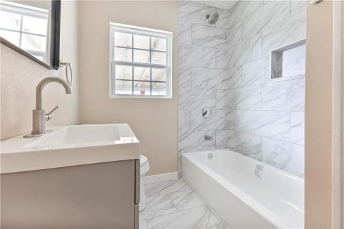 a white bathroom with a sink and a bath tub at 5 beds 2 bath, sleep 10 in Corpus Christi