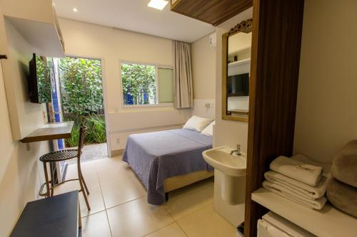 a bedroom with a bed and a sink and a bathroom at K2 RESIDENCE Campinas in Campinas