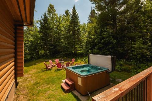 a hot tub on a deck with a table and chairs at Fiddler Lake Resort - Rabbit 66 in Mille-Isles