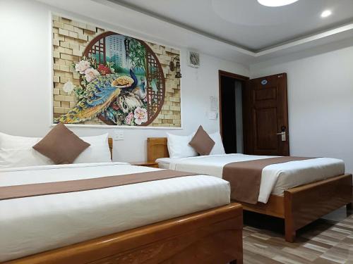 two beds in a room with a painting on the wall at HP Truong Hotel Phu Quoc in Phú Quốc