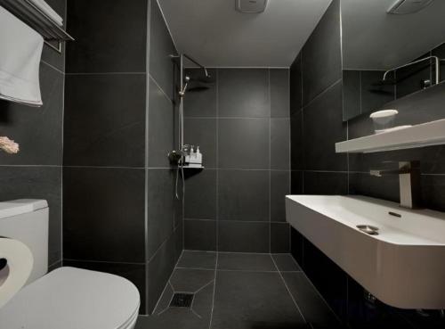 a bathroom with a toilet and a sink at Pampas Hotel Jeju in Jeju