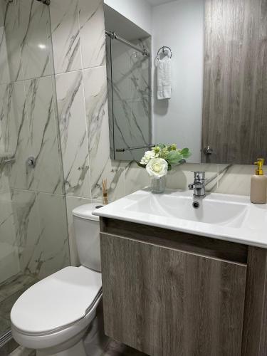 a bathroom with a sink and a toilet and a mirror at Apartamento para 6, Aeropuerto, Cerca Parque del Café, Horeb Confort in La Tebaida
