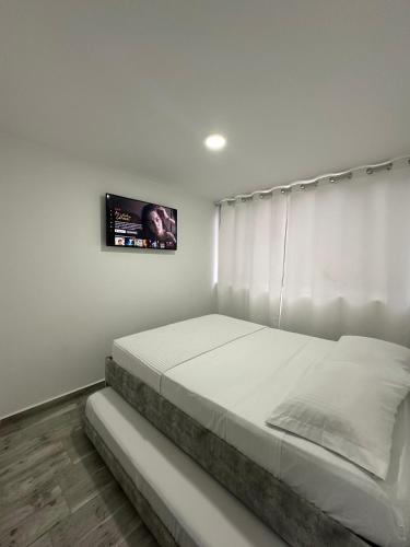 a bedroom with a bed with a tv on the wall at Apartamento para 6, Aeropuerto, Cerca Parque del Café, Horeb Confort in La Tebaida