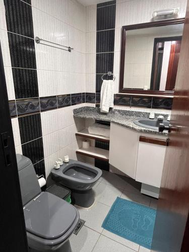 a bathroom with a toilet and a sink and a mirror at Executive Flat in Apart Hotel in Campinas