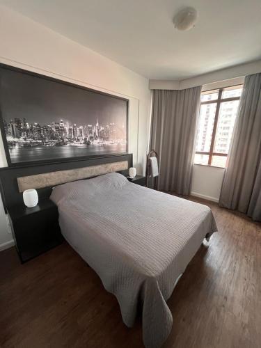 a bedroom with a bed with a large painting on the wall at Executive Flat in Apart Hotel in Campinas