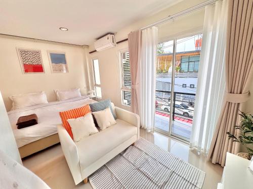 a bedroom with a bed and a couch and a window at Boon Poshtel Hatyai in Sathani Hat Yai
