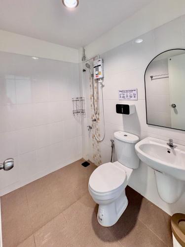 a white bathroom with a toilet and a sink at Boon Poshtel Hatyai in Sathani Hat Yai