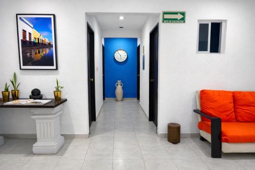 a hallway with an orange couch and a clock on the wall at Hotel Puesta del Sol in Campeche