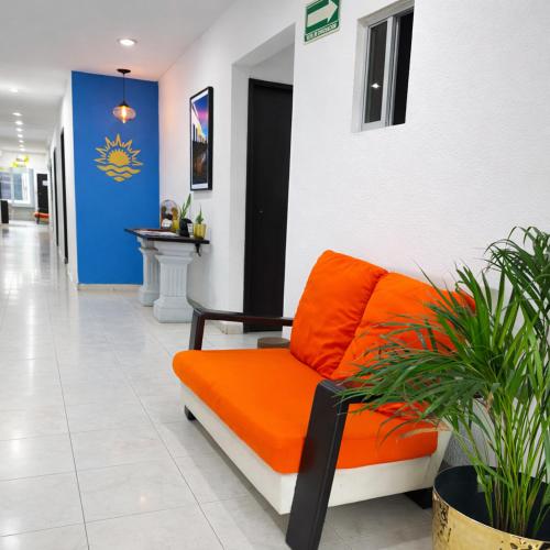 an orange couch sitting in a hallway with plants at Hotel Puesta del Sol in Campeche
