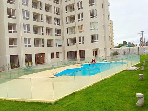 a large building with a swimming pool in front of it at Apartamento Peñuelas in Coquimbo
