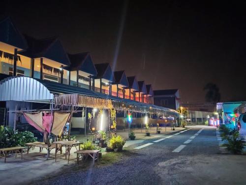 a building with tables and benches at night at ภูมิคิมมินทร์ รีสอร์ท & สปา in Ban Chai Na
