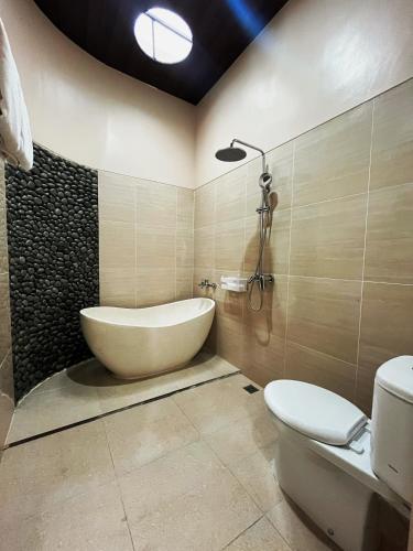 a bathroom with a tub and a toilet and a sink at The Olla Villa in Yogyakarta