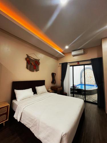 a bedroom with a large white bed and a window at The Olla Villa in Yogyakarta