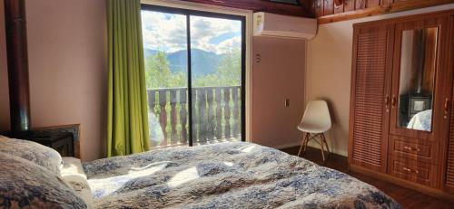a bedroom with a bed and a large window at casa caburgua en cerro in Caburgua