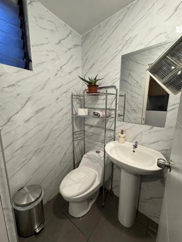 a white bathroom with a toilet and a sink at Antuquita's House in Cusco