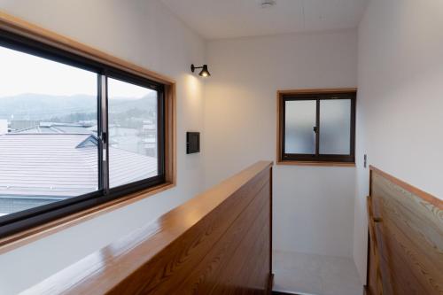 a room with a large window and a wooden floor at まちやど半歩 in Shimo-suwa