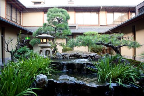 a garden with a pond in front of a building at Shiki Resort Kyoto Kamogawaso in Kyoto