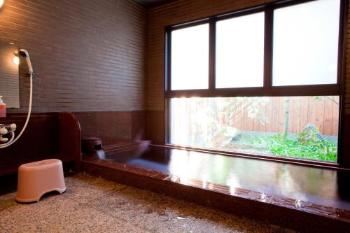 a bathroom with a bath tub and a window at Shiki Resort Kyoto Kamogawaso in Kyoto