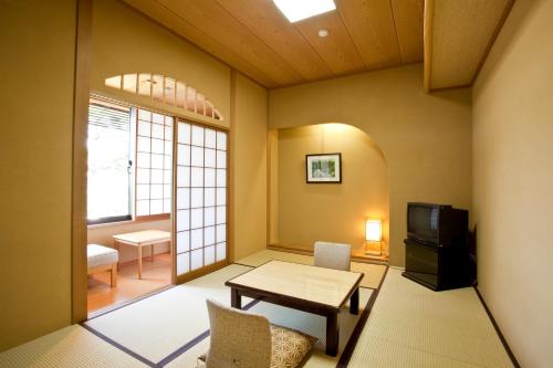 a living room with a table and a tv at Shiki Resort Kyoto Kamogawaso in Kyoto