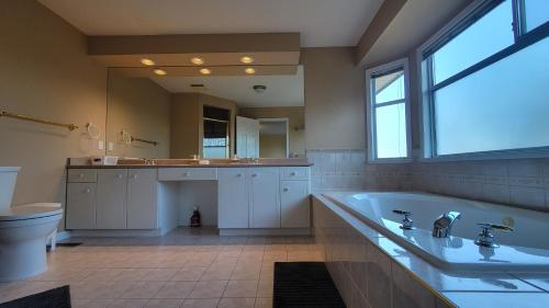 a large bathroom with a tub and a large mirror at 7Bedroom Beautiful and spacious home in Surrey