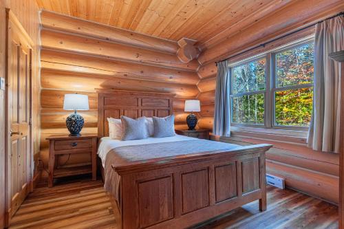 a bedroom with a bed in a log cabin at Fiddler Lake Resort - Rabbit 12 in Mille-Isles