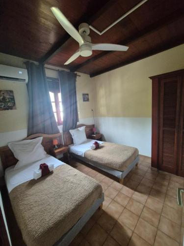 a bedroom with two beds and a ceiling fan at La Pointe d'Argent in Pointe-Noire