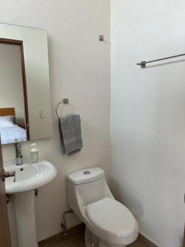 a white bathroom with a toilet and a sink at Gran departamento con alberca, terraza y vista a lago en Lago Luna - 5 minutos de Chante Spa in Chantepec