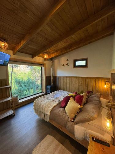 a large bed in a room with a window at Wincarayen Lodge & Cabañas in Panguipulli