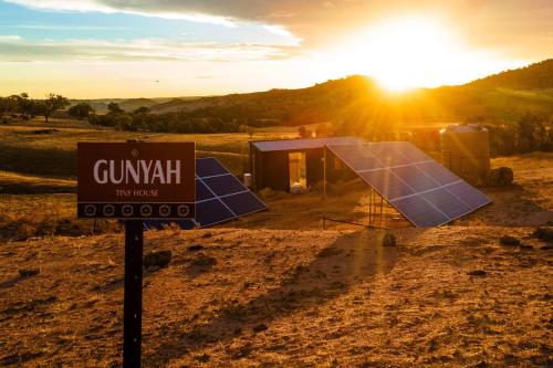 a sign in front of a small house with the sunset at Gunyah by Tiny Away in Mount McDonald