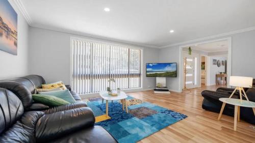 a living room with a leather couch and a table at Alka Beach House in Callala Beach