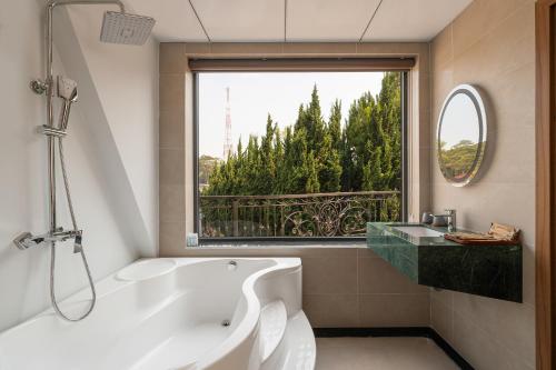 a bathroom with a tub and a large window at Khách sạn Brume Đà Lạt in Da Lat
