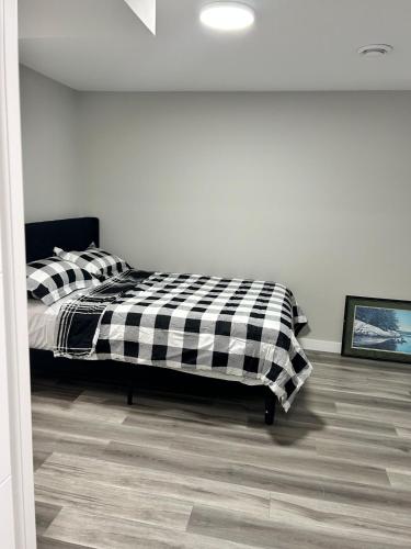 a bedroom with a bed with a black and white blanket at Spacious and Stylish Private Basement Suite - 1 bed and 1 rec room in Winnipeg