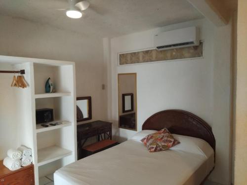 a small bedroom with a bed and a shelf at Bungalow Encanto in Zihuatanejo