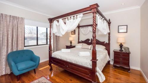a bedroom with a canopy bed and a blue chair at Ruthmor Villas in Toowoomba