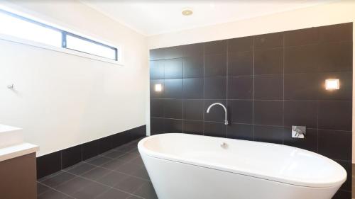 a bathroom with a white tub and black tiles at Ruthmor Villas in Toowoomba