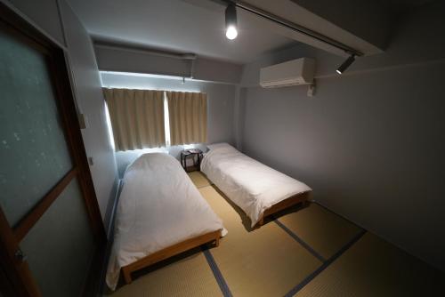 ein kleines Zimmer mit zwei Betten und einem Fenster in der Unterkunft あわい in Kure