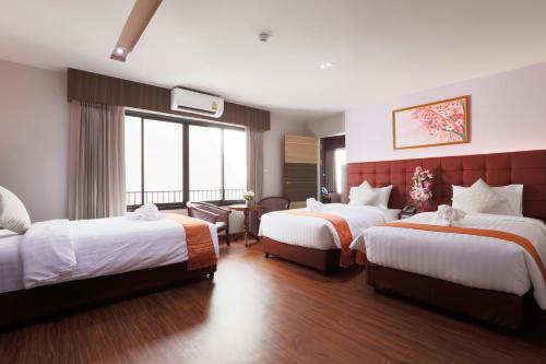 a hotel room with two beds and a large window at Grandpink park hotel in Hat Yai